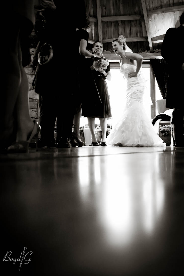 bride laughing with hands on her hips in front of soft window light