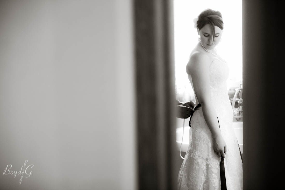 bride getting ready as her father ties the back fo her dress