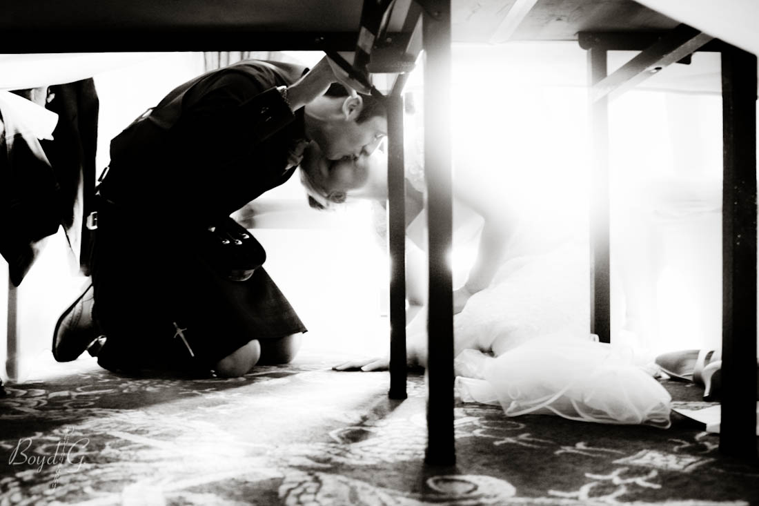 Bride and groom kiss under the table as is the tradition when guests start tapping their glasses.