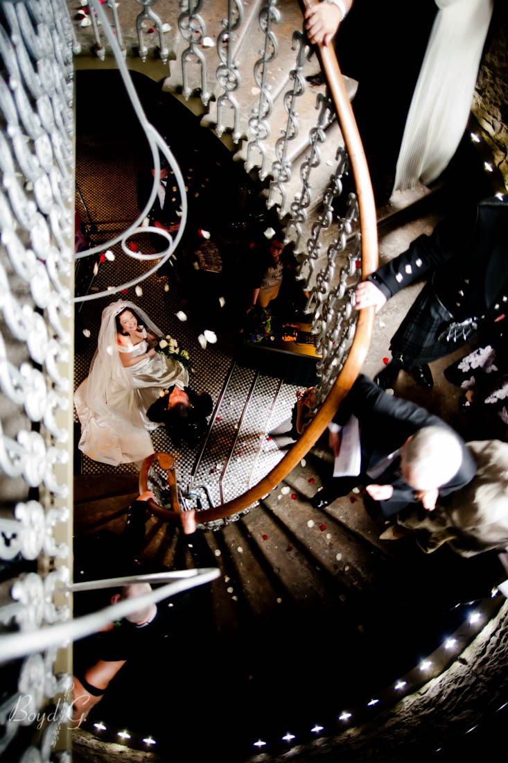 Bride looks up at falling petals after she comes down a staircase right after the bride and groom said their vows.